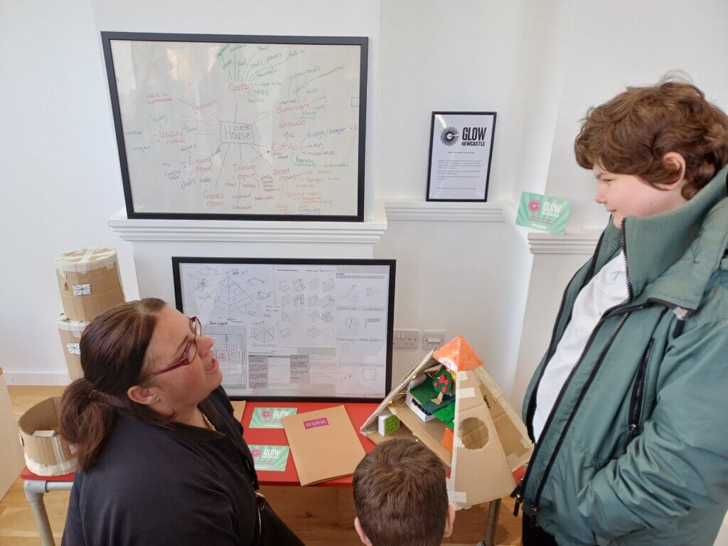 A pupil at NBS explains his project designs and model to a parent at The Farrell Centre, Newcastle University